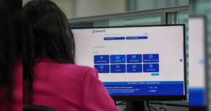 Uma pessoa usa um computador para acessar serviços online de trânsito em um ambiente de atendimento