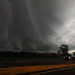 Nuvens escuras e densas sobre rodovia com veículo circulando em meio a tempestade