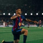Um jogador comemora no gramado de um estádio lotado à noite