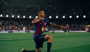 Um jogador comemora no gramado de um estádio lotado à noite