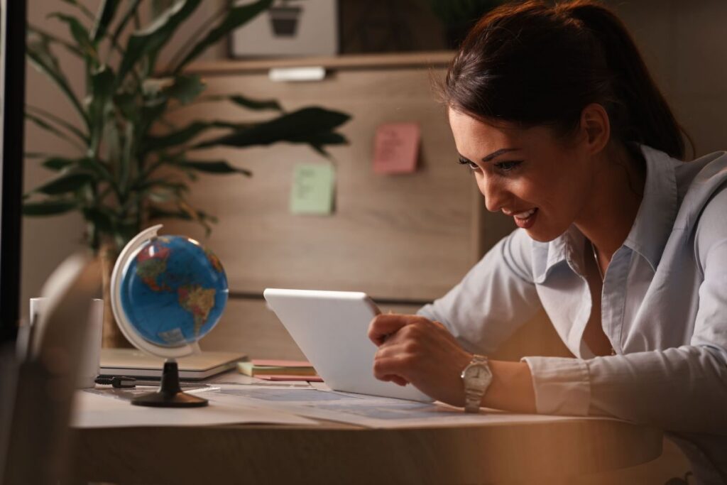 Uma mulher olha atenta para um tablet em uma mesa com um globo ao lado