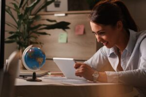 Uma mulher olha atenta para um tablet em uma mesa com um globo ao lado
