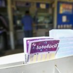 Um grupo de pessoas em frente a um balcão com cartelas de lotofácil na frente