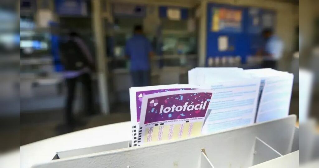 Um grupo de pessoas em frente a um balcão com cartelas de lotofácil à vista