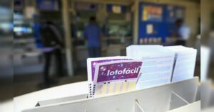 Um grupo de pessoas em frente a um balcão com cartelas de lotofácil à vista
