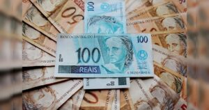 Notas de cem reais espalhadas sobre outras cédulas de valores menores