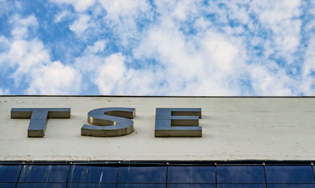 Letras metálicas com as siglas TSE em um prédio sob céu azul com nuvens