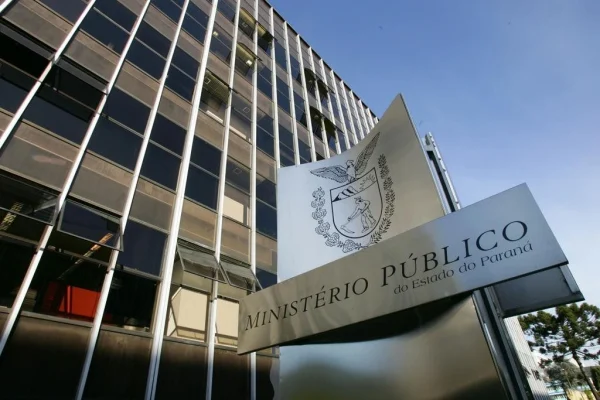 Um prédio moderno com uma placa que exibe o nome de um órgão público estadual sob céu azul claro