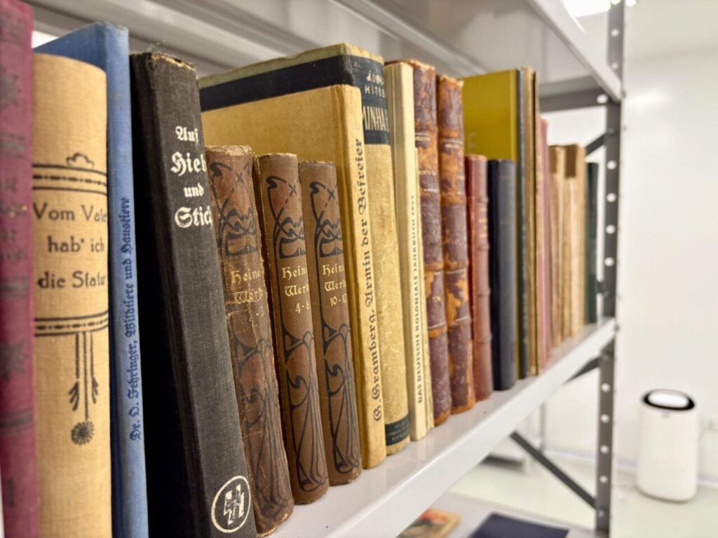 Livros antigos em prateleira com capas em alemão e símbolos nazistas