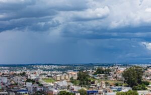Céu nublado sobre uma cidade com edifícios e vegetação ao fundo