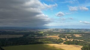 Vista aérea de campos cultivados e áreas florestadas sob céu parcialmente nublado