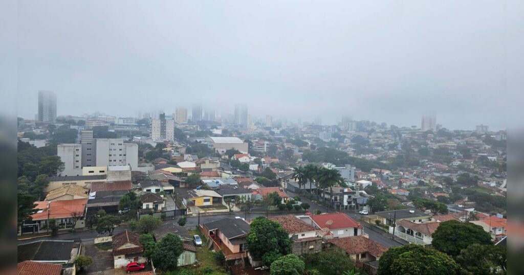 Uma cidade sob neblina com casas e prédios ao fundo em um dia nublado