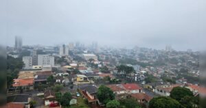 Uma cidade sob neblina com casas e prédios ao fundo em um dia nublado