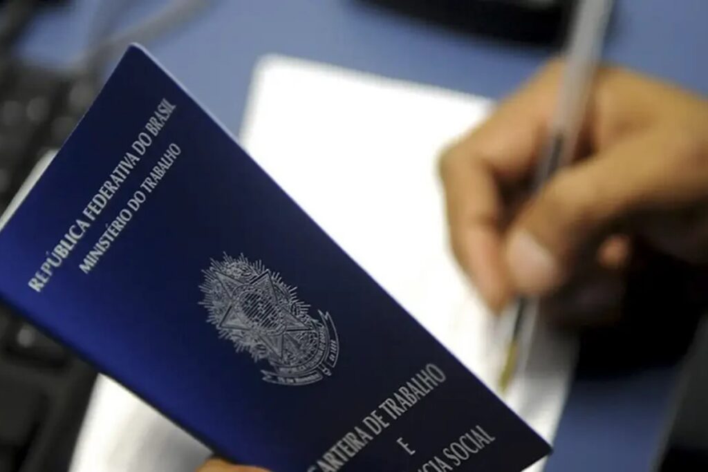 Um documento azul com brasão do governo é segurado enquanto uma mão escreve em papel