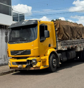 Caminhão amarelo com danos na frente parado na rua após colisão