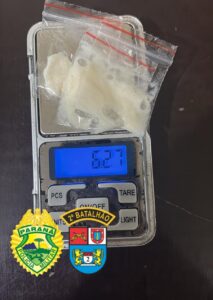 Sacos plásticos com substância branca sobre balança digital marcando 6,27 gramas, com emblemas da Polícia Militar do Paraná