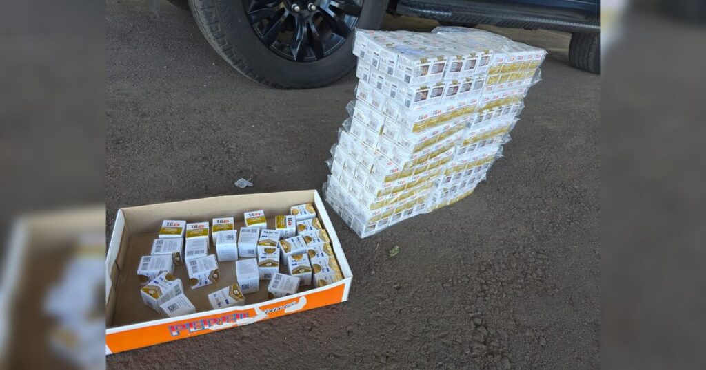 Pilhas de caixas de medicamentos em caixas abertas ao lado de um veículo em pista de rodagem