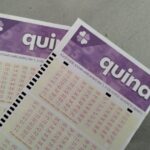 Dois volantes da loteria Quina com números marcados em uma superfície plana