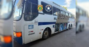 Um ônibus com portas abertas e sacos apreendidos em sua lateral