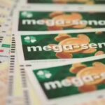 Vários volantes da Mega-Sena espalhados sobre uma superfície com destaque para o nome do jogo em alguns deles