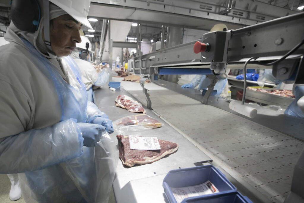 Um homem de terno trabalha em uma linha de produção de alimentos em ambiente industrial