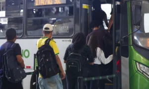 Um grupo de pessoas entra em um ônibus em uma parada urbana