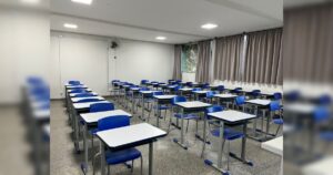 Sala de aula vazia com carteiras e cadeiras azuis organizadas em fileiras