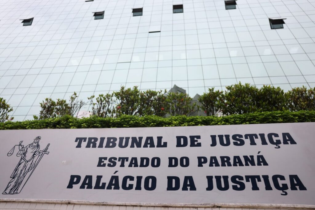 Um prédio de vidro com uma placa indicando o Tribunal de Justiça do Estado do Paraná e o Palácio da Justiça