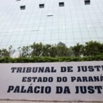Um prédio de vidro com uma placa indicando o Tribunal de Justiça do Estado do Paraná e o Palácio da Justiça