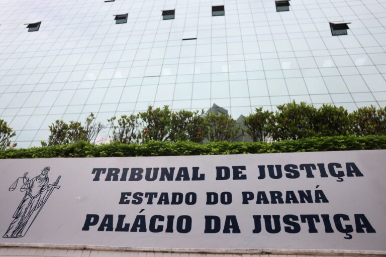 Um prédio de vidro com uma placa indicando o Tribunal de Justiça do Estado do Paraná e o Palácio da Justiça