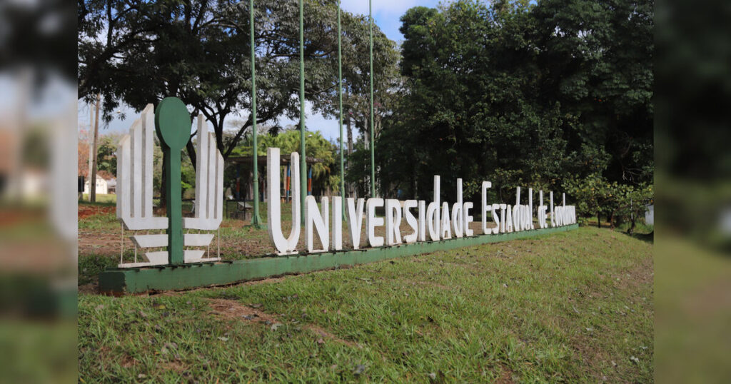 Um grande letreiro com o nome de uma universidade em um gramado arborizado