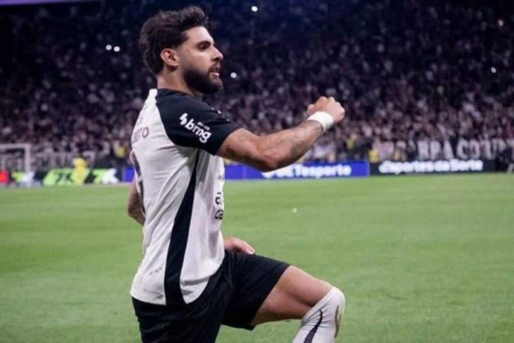 Um jogador comemora no gramado de um estádio lotado durante partida noturna