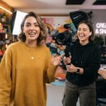 Duas mulheres em um estúdio com equipamentos de gravação e iluminação profissional